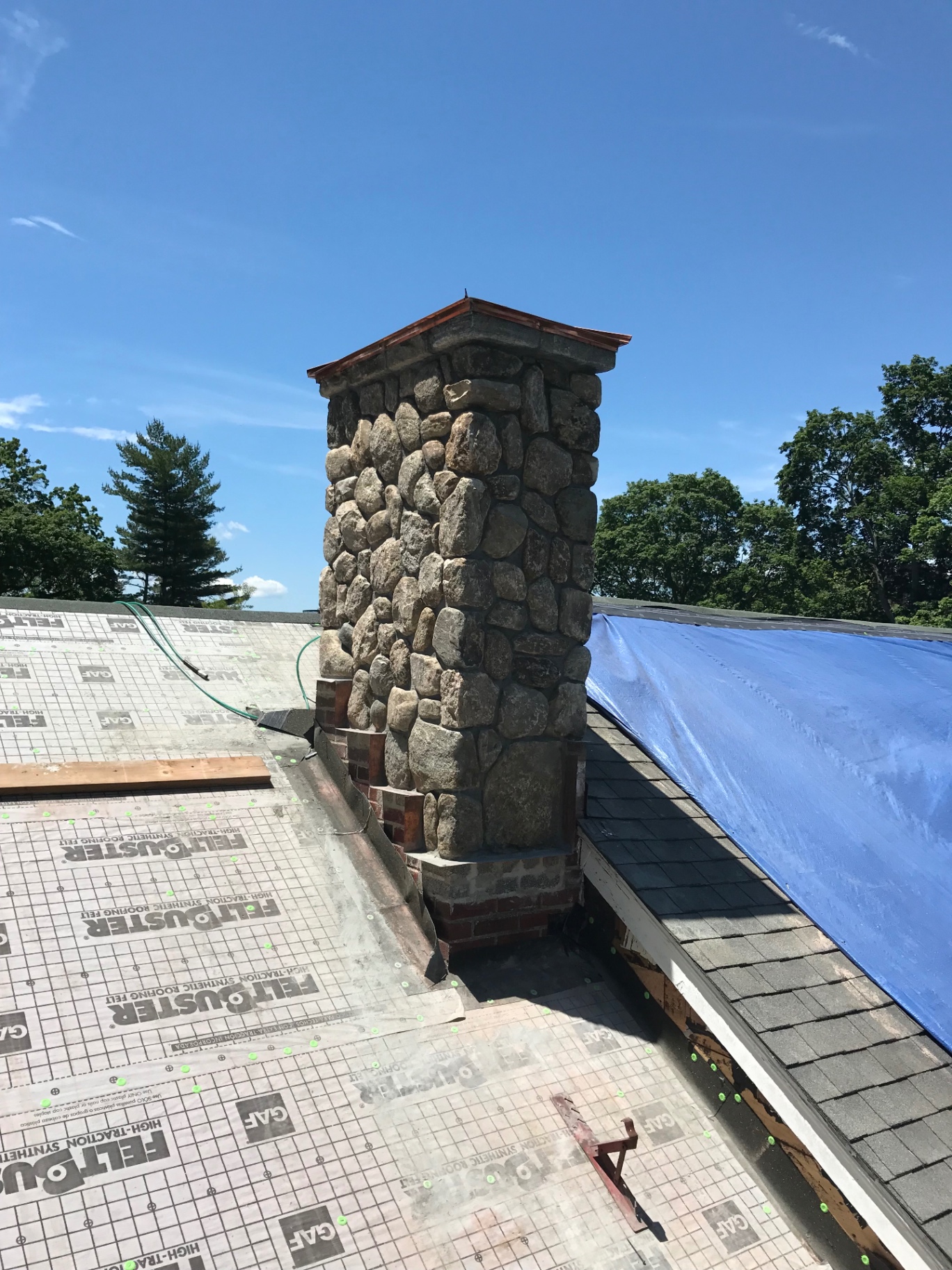 Fieldstone chimney with copper cap on a roofline